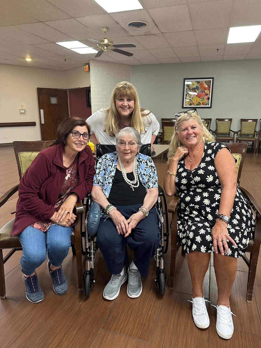 a seated resident with three staff members around, all smiling
